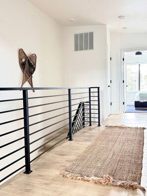 A modern interior with a black metal railing, a woven rug, and a decorative wall piece. - Mountain Modern Retreat w Hot Tub 3Bed Winter Park (Fraser)