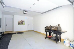 A garage with a barbecue grill, two doors, and a bear painting on the wall. - Mountain Modern Retreat w Hot Tub 3Bed Winter Park (Fraser)