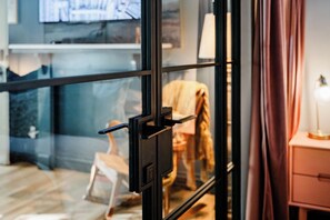 Une pièce avec une porte vitrée, un lit, une table de chevet et une lampe.