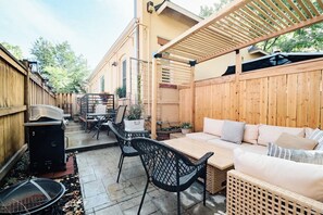 A patio area with a wooden fence, a grill, outdoor furniture, and a pergola. - Boutique 1BD Townhome w/Great Patio in Wash Park (Denver)