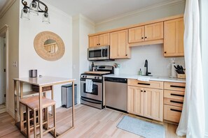 Une cuisine moderne avec des meubles en bois, des appareils en acier inoxydable et un miroir rond accroché au mur.