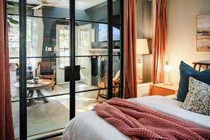 A hotel room with a bed, a nightstand, a lamp, and a view through a glass door to a dining area. - Boutique 1BD Townhome w/Great Patio in Wash Park (Denver)