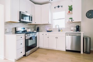 A modern kitchen with white cabinetry, stainless steel appliances, and a dishwasher. - Home Away from Home w/Sauna 4BD|2BA | Berkley (Denver)