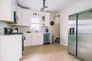 A modern kitchen with white cabinetry, stainless steel appliances, and a built-in dishwasher. - Home Away from Home w/Sauna 4BD|2BA | Berkley (Denver)