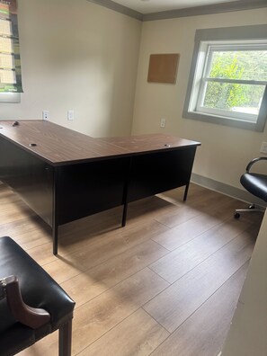 A conference room with a long table, black chairs, and a window with a view of greenery.