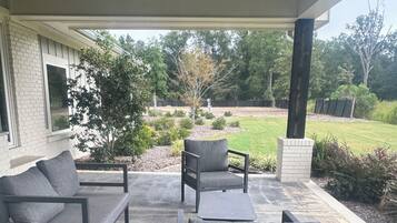 Un patio al aire libre con piso de concreto, dos sillones tapizados en gris, una mesita y un sofá.