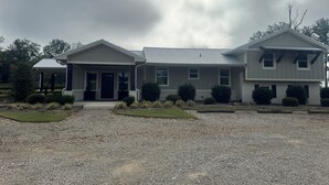 A two-story house with a covered porch, a gravel driveway, and a well-maintained lawn.