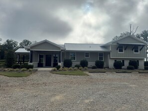 A two-story house with a covered porch, a gravel driveway, and a well-maintained lawn.