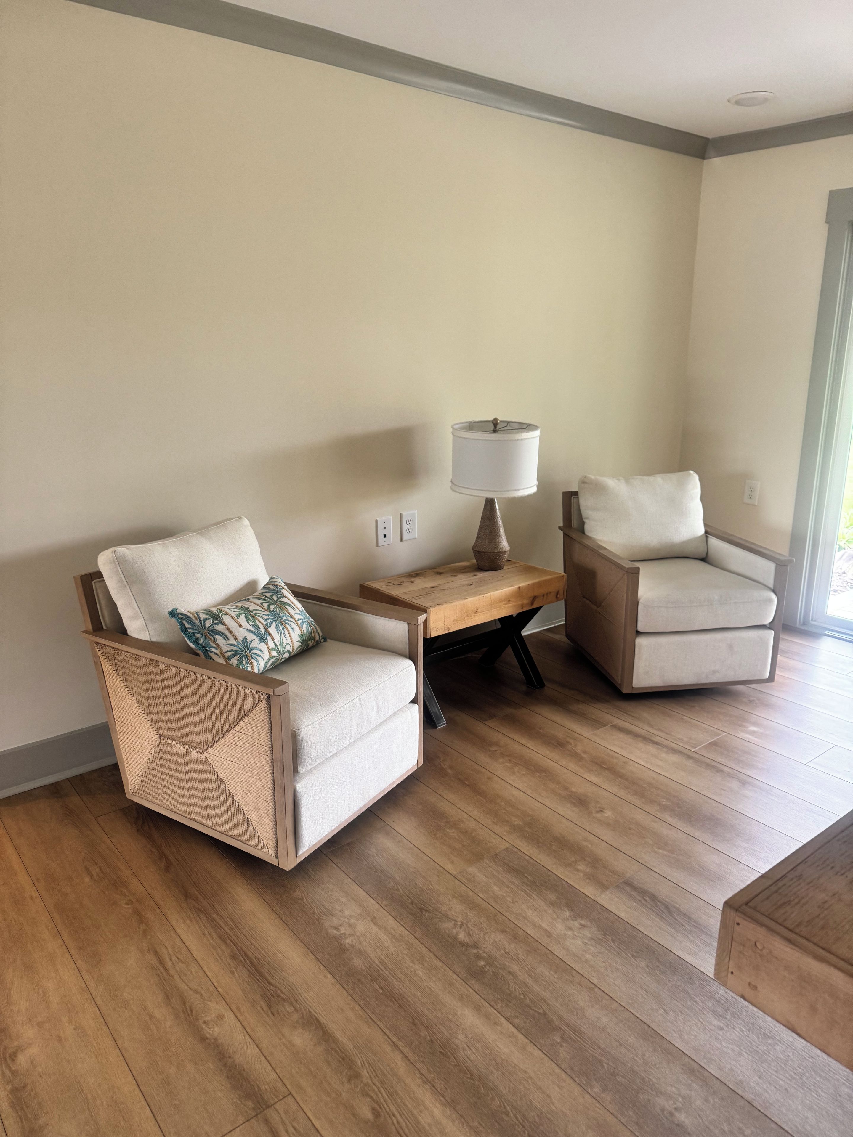 Een kamer met twee fauteuils, een houten bijzettafeltje en een vloerlamp.