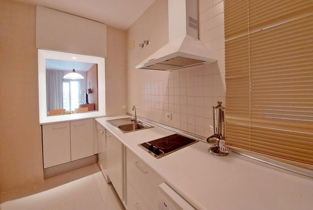 A modern kitchen with white cabinetry, a stainless steel sink, and a built-in stovetop.