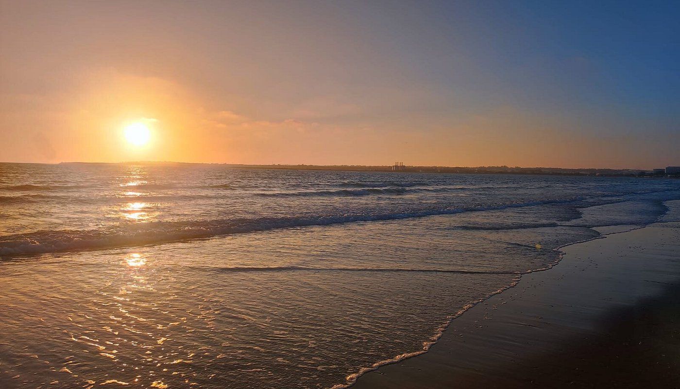 A beach with waves and a sunset.