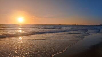 A beach with waves and a sunset.