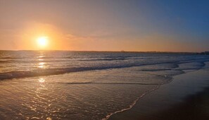 Een strand met golven en een zonsondergang.