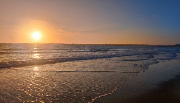 A beach with waves and a sunset.