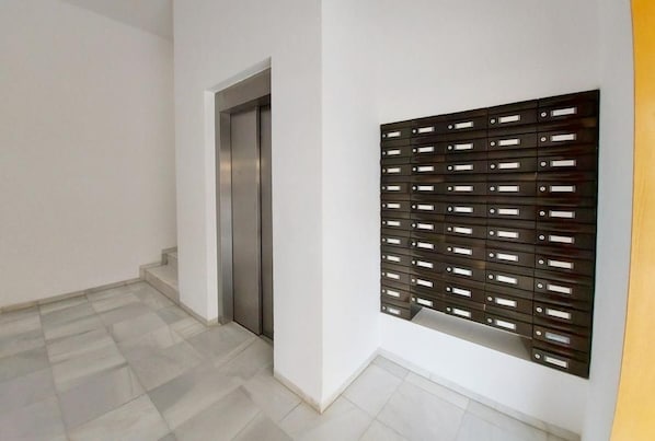Un pasillo con un ascensor metálico y un mueble de almacenamiento empotrado con varios compartimentos.