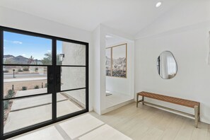 Ein modernes Interieur mit einer großen Schiebeglasdoor zum Patio, einer Bank und einem wandmontierten Spiegel.
