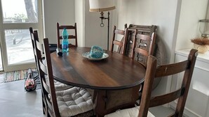 A dining area with a round wooden table, cushioned chairs, a lamp, and a window with a view of the outdoors. - TORRE SARACENA. Villa in Capri (M. Piccola) with beach access and a large terrace (Campania)