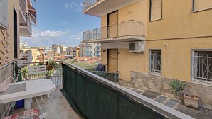 Ein Wohngebäude mit Balkonen, einer Terrasse mit Tisch und Stühlen und Blick auf die umliegende Nachbarschaft.