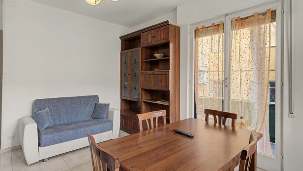 Ein Essbereich mit Holztisch, Stühlen, einer Couch und einem Schrank.