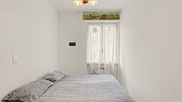 Een slaapkamer met een bed, een schilderij boven de deur en een kroonluchter.