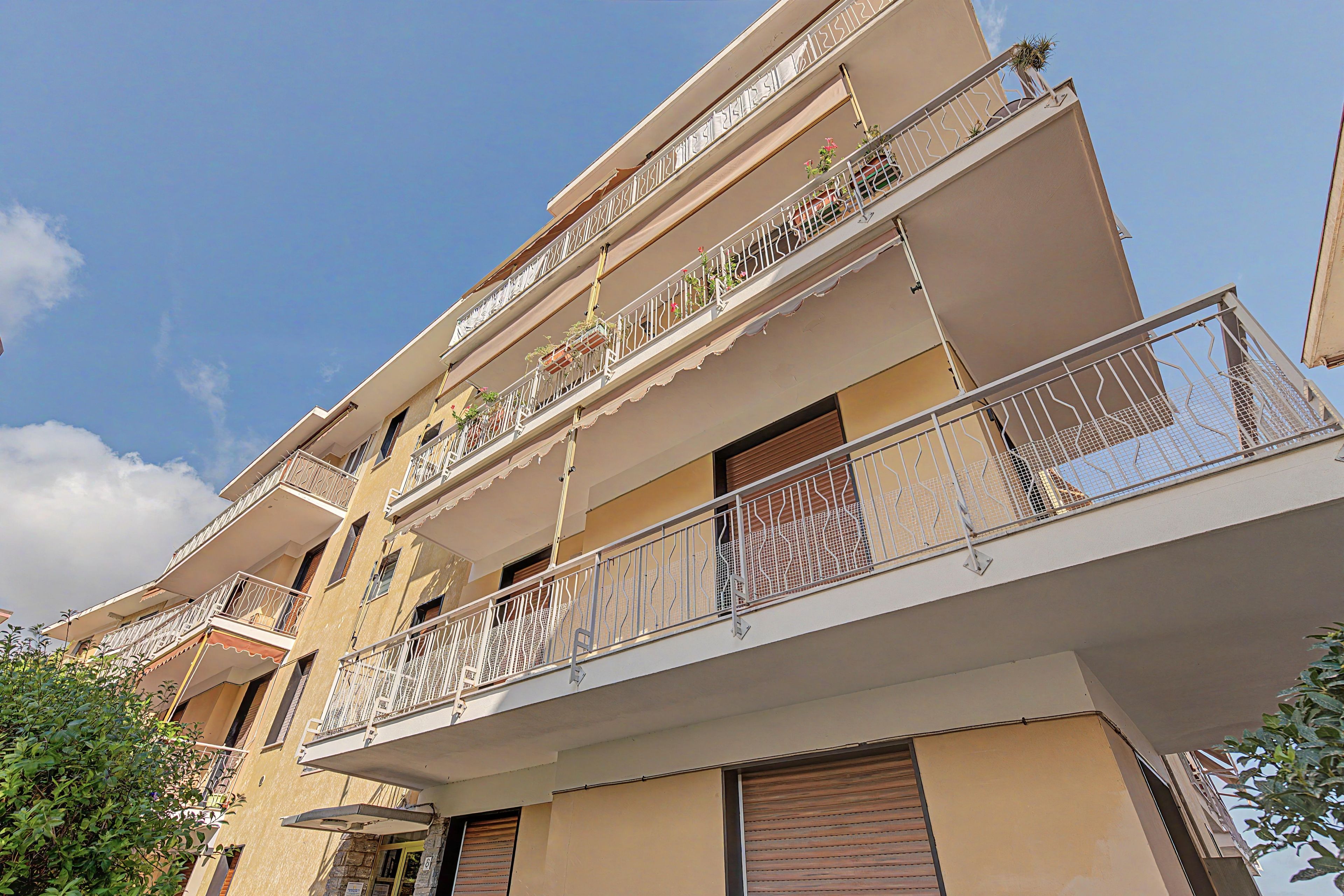A multi-story residential building with balconies, some with plants.