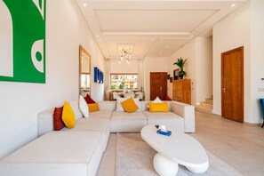 Un salon moderne avec un canapé d’angle, une table basse et un coin repas à l’arrière-plan.