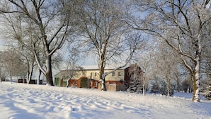 Et sneklædt landskab med et hus og træer.