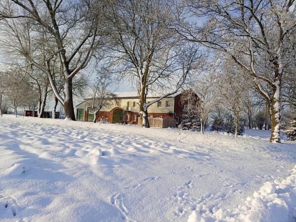 A snow-covered landscape with a house and trees.
