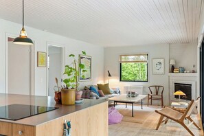Ein modernes Wohnzimmer mit Kamin, Essbereich und Küchenzeile.