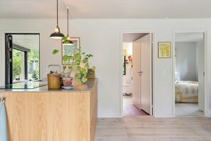 Ein modernes Interieur mit Kücheninsel, Topfpflanzen und Blick ins Badezimmer.
