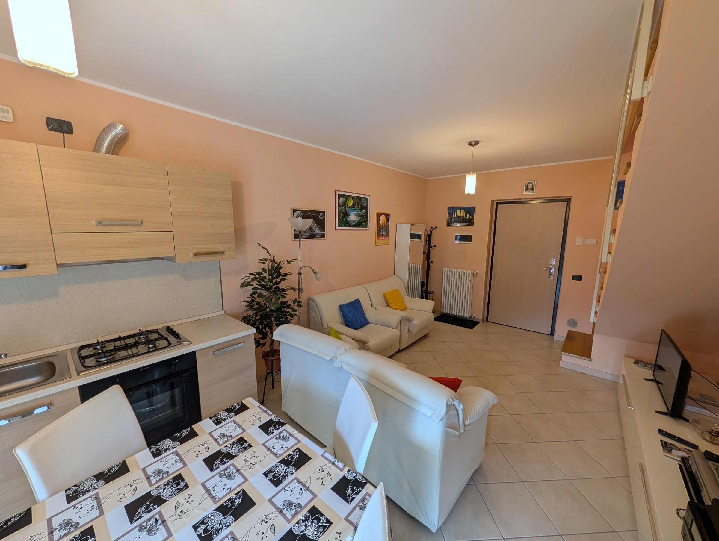 Een compacte woonruimte met kitchenette, eethoek, bank en radiator.