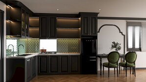 Una cocina moderna con armarios oscuros, piso de madera en patrón de espiga y un comedor con dos sillas tapizadas en verde.