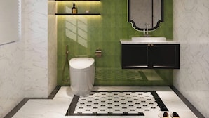 Un baño con inodoro blanco, tocador negro, pared de acento verde y alfombra estampada en el suelo.