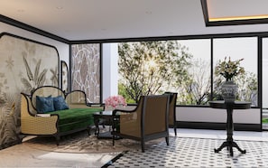 A modern interior with a sofa, chairs, a small table, and a large window offering a view of trees. - Mayan Hanoi Residence (Hai Ba Trung)