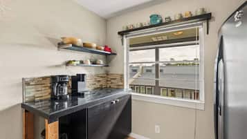 A compact kitchen with a built-in coffee maker, a window with a view, and a stainless steel refrigerator.