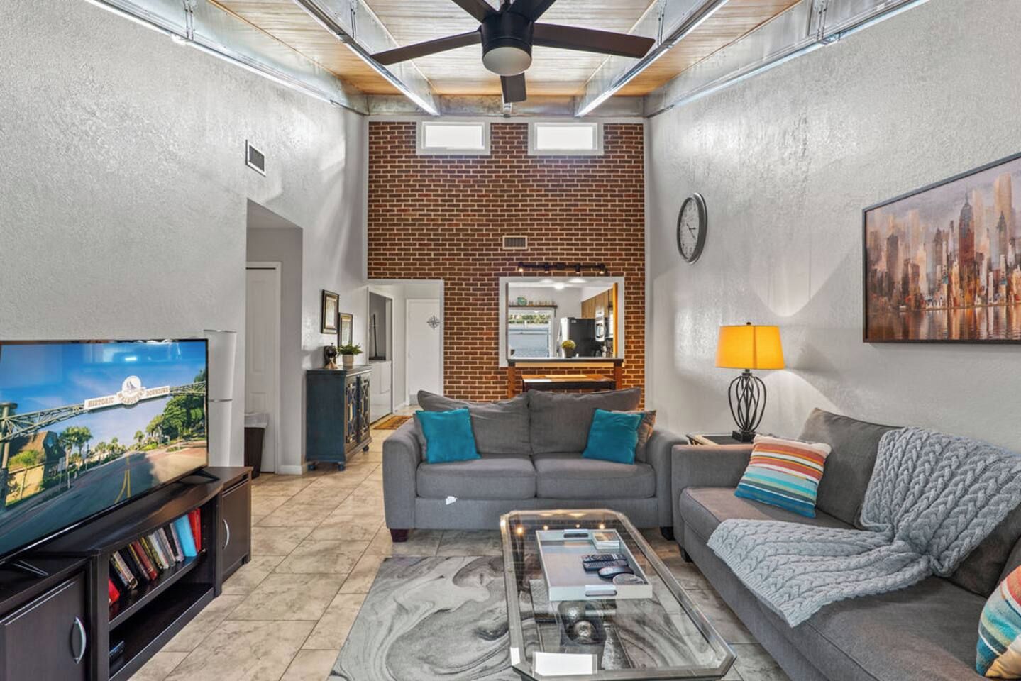 A living room with a television, sofas, a coffee table, and a brick wall.