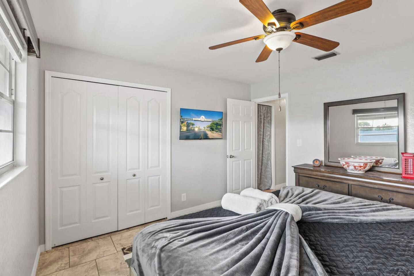 A bedroom with a bed, a ceiling fan, a window, and a door.