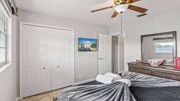 A bedroom with a bed, a ceiling fan, a window, and a door.