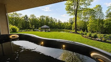 Un bain à remous à bords incurvés, entouré d’une pelouse bien entretenue et d’arbres.