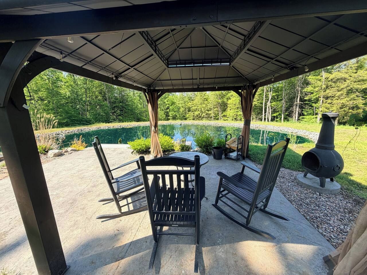 Un patio exterior con zona de estar techada, una mesa y un estufa de leña.