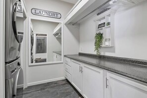 Eine Küche mit einem Edelstahl-Kühlschrank, einem Schild mit der Aufschrift 'LAUNDRY' und einer Pflanze auf der Arbeitsplatte.
