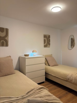 Ein Schlafzimmer mit zwei Betten, einem Schminktisch und einer Deckenleuchte.
