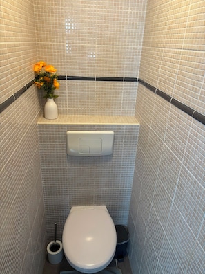 Ein kleines Badezimmer mit Toilette, Bidet und Toilettenpapierhalter.