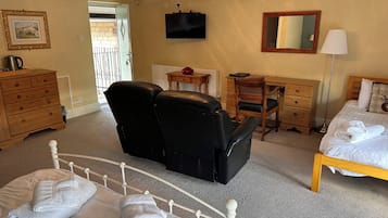 Habitación de hotel con cama, escritorio, silla, cómoda, televisor y lámpara.