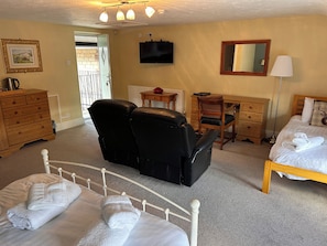 A hotel room with a bed, a desk, a chair, a dresser, a television, and a lamp. - The Ganton Greyhound (Scarborough)