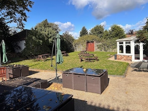 An outdoor patio area with picnic tables, a covered seating area, and a small building. - The Ganton Greyhound (Scarborough)