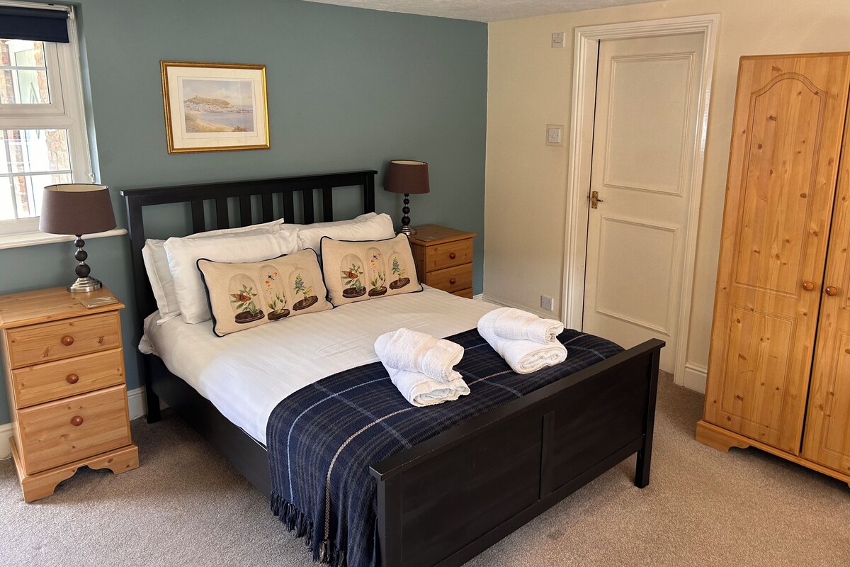 A bedroom with a bed, nightstands, a wooden wardrobe, and a framed picture on the wall.
