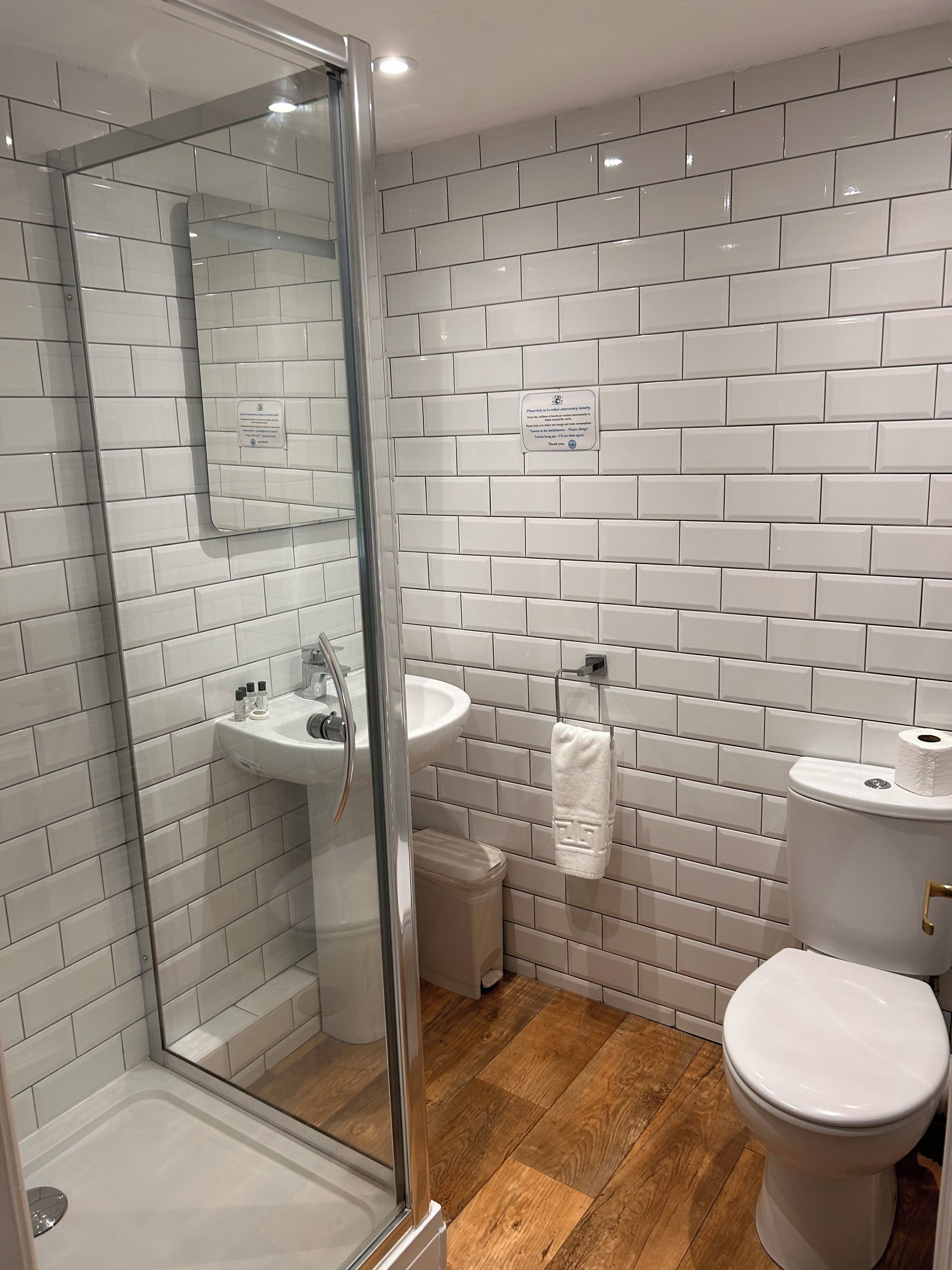 A modern bathroom with a glass shower enclosure, a sink, a toilet, and a mirror.