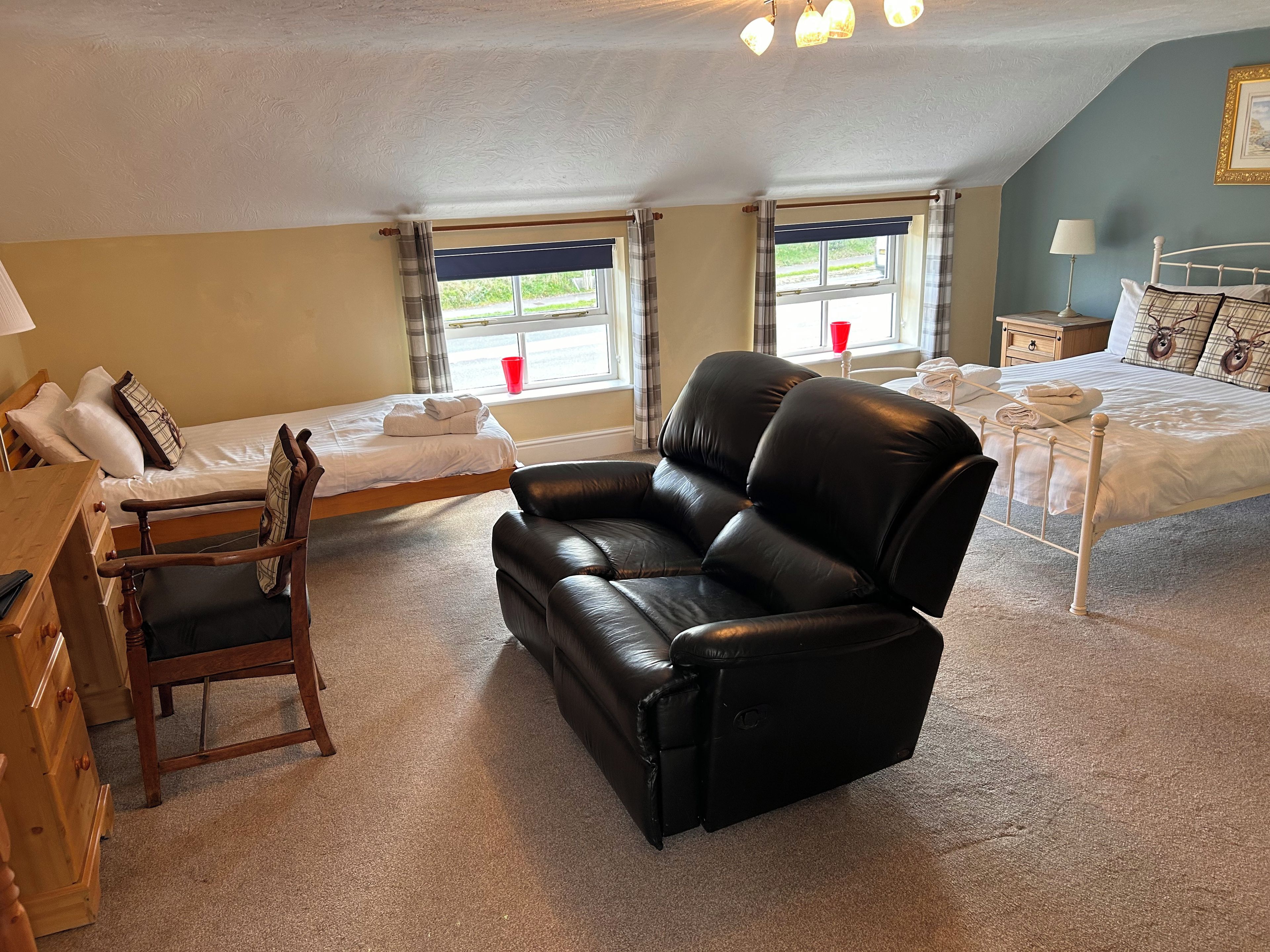 Ein Zimmer mit einem Bett, einem Schlafsofa, einem Schreibtisch und einem fenster mit Vorhängen.