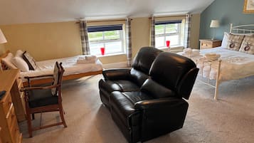 A room with a bed, a sofa, a desk, and a window with curtains.